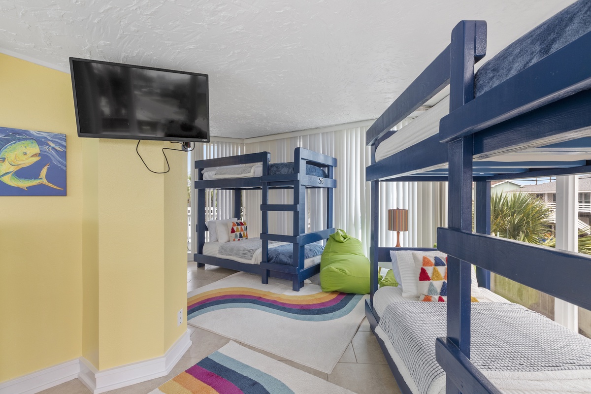 Your kids will love this colorful bunk room with multiple beds, fun rainbow rug, and their own TV for movie nights.