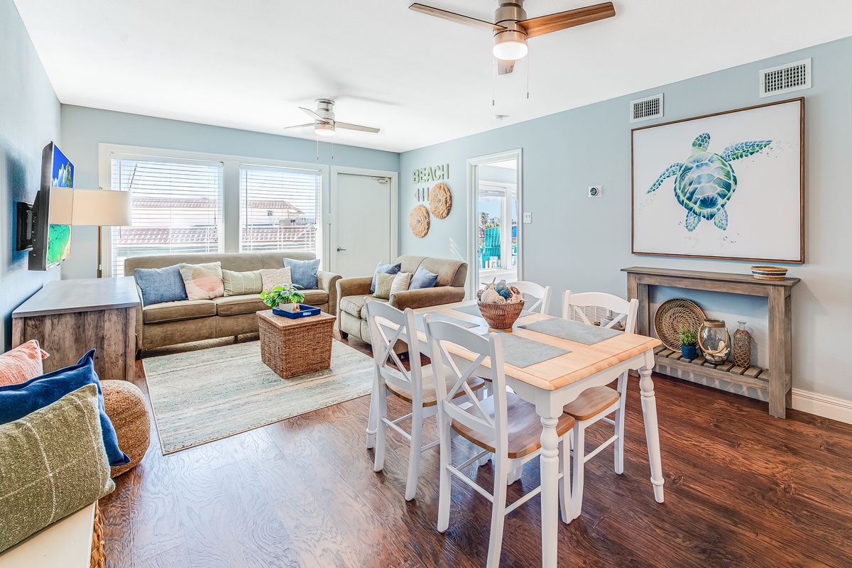 Relax in your coastal-themed living space where soft blue walls and beach-inspired art create a serene atmosphere for dining and unwinding.