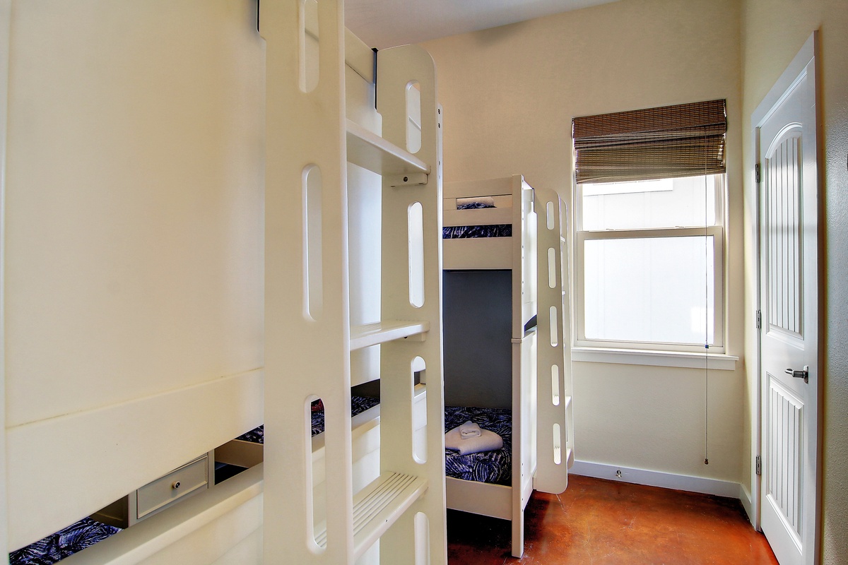 Your cozy bunk room offers comfortable sleeping with natural light streaming through bamboo blinds, perfect for restful nights.