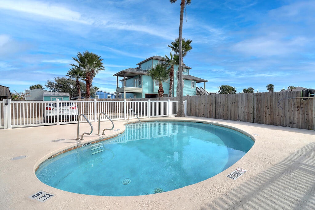 Crystal-clear pool awaits your refreshing dip under swaying palms and endless blue skies in this tropical coastal setting.