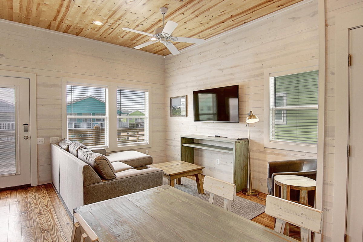 Relax in your bright, airy living space with rustic wood walls and modern comfort. Natural light streams through windows.
