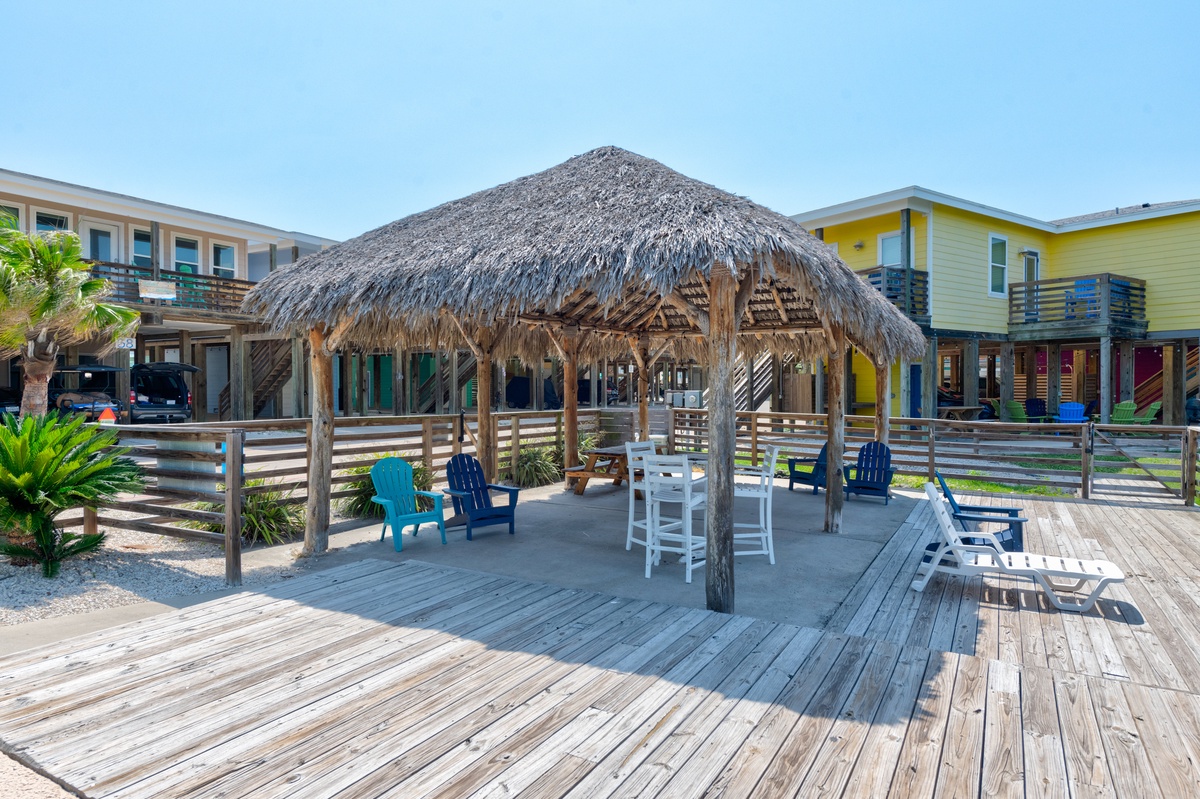 Relax in your own tropical paradise with this thatched-roof tiki hut featuring comfortable seating and tables for memorable gatherings.