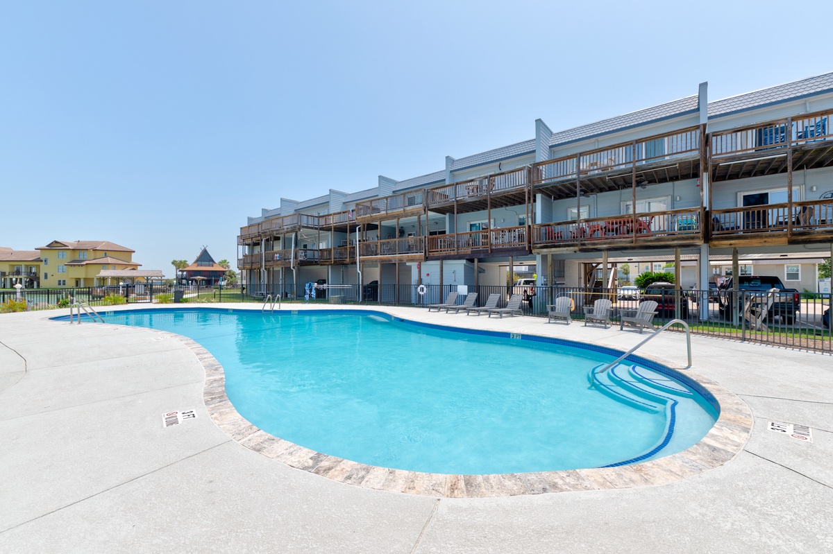 The property features a spacious outdoor pool surrounded by multi-level accommodations with expansive balconies, perfect for sunny days and relaxation.