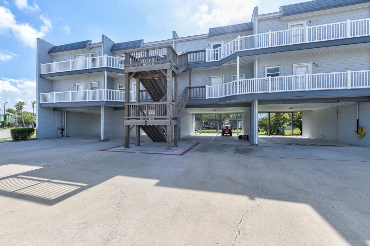 Multi-story beachside property with covered parking and balconies overlooking the coastal area.