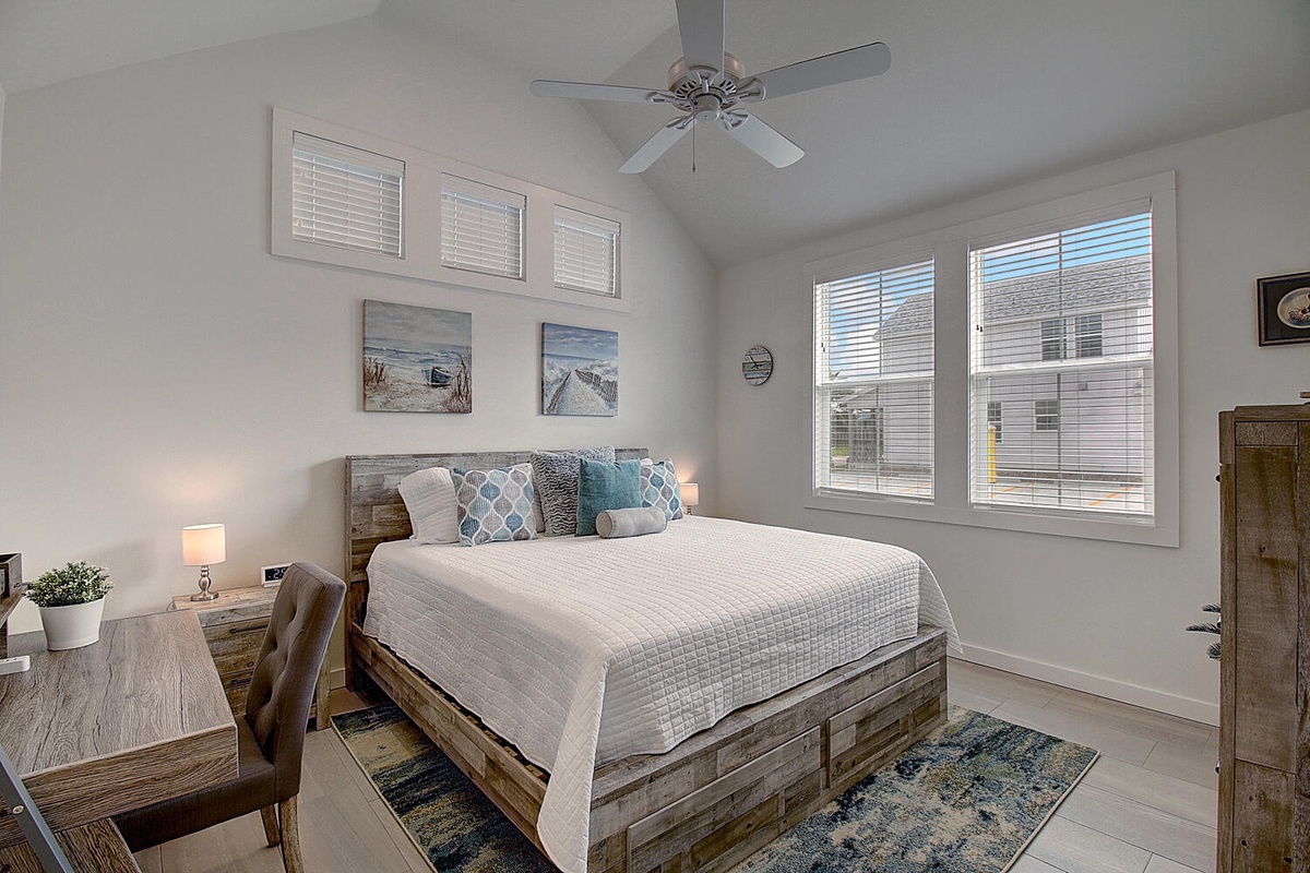 Drift off to sleep in your peaceful bedroom featuring a rustic wooden bed, soft linens, and coastal artwork that brings seaside serenity indoors.