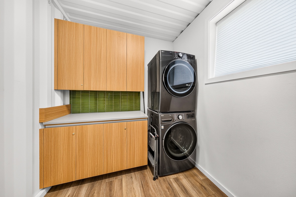 Your dedicated laundry space features modern stacked washer and dryer with stylish cabinetry and counter space for folding.