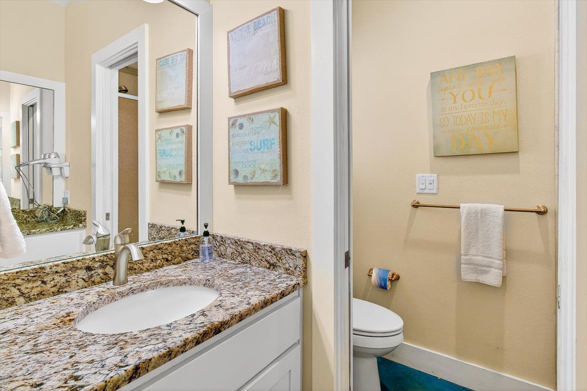 Step into your private bathroom with granite countertops, fresh towels, and coastal artwork creating a peaceful retreat.