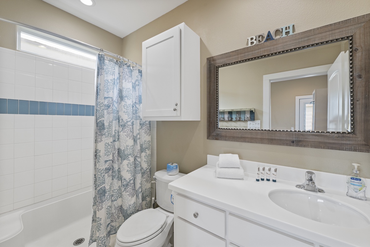 Your bright, beach-themed bathroom features a full tub and shower combo, crisp white linens, and coastal decor to start your day refreshed.
