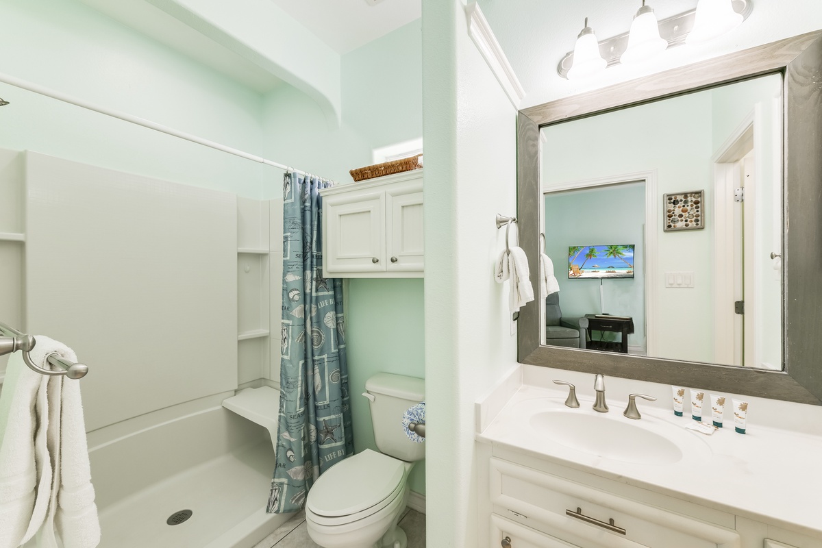 Freshen up in your private bathroom featuring soft mint walls, coastal charm, and thoughtful amenities for your comfort.
