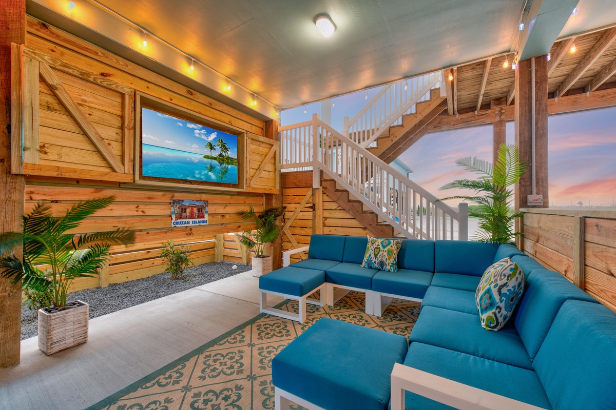 Unwind in your tropical living room with plush blue sectional seating, warm wood accents, and vibrant island artwork.