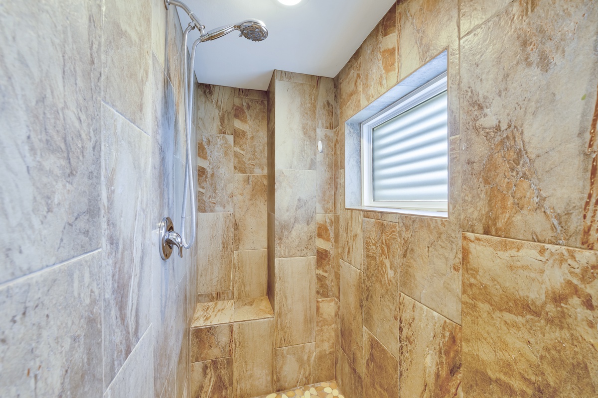 Your private spa-style shower features stunning natural stone walls and a built-in bench for ultimate relaxation.