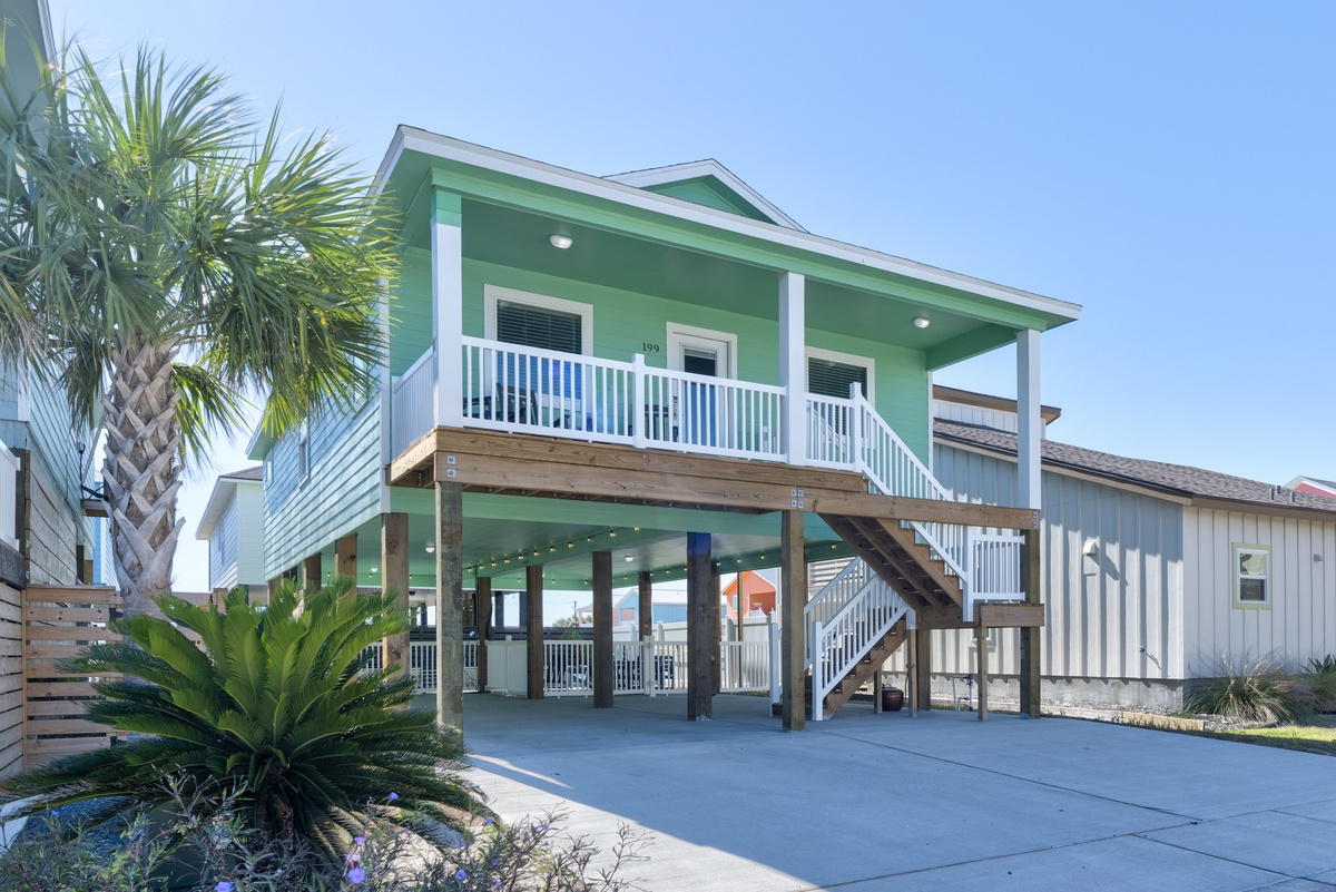 Charming coastal cottage with tropical landscaping creates an inviting beachside atmosphere in a picturesque neighborhood setting.