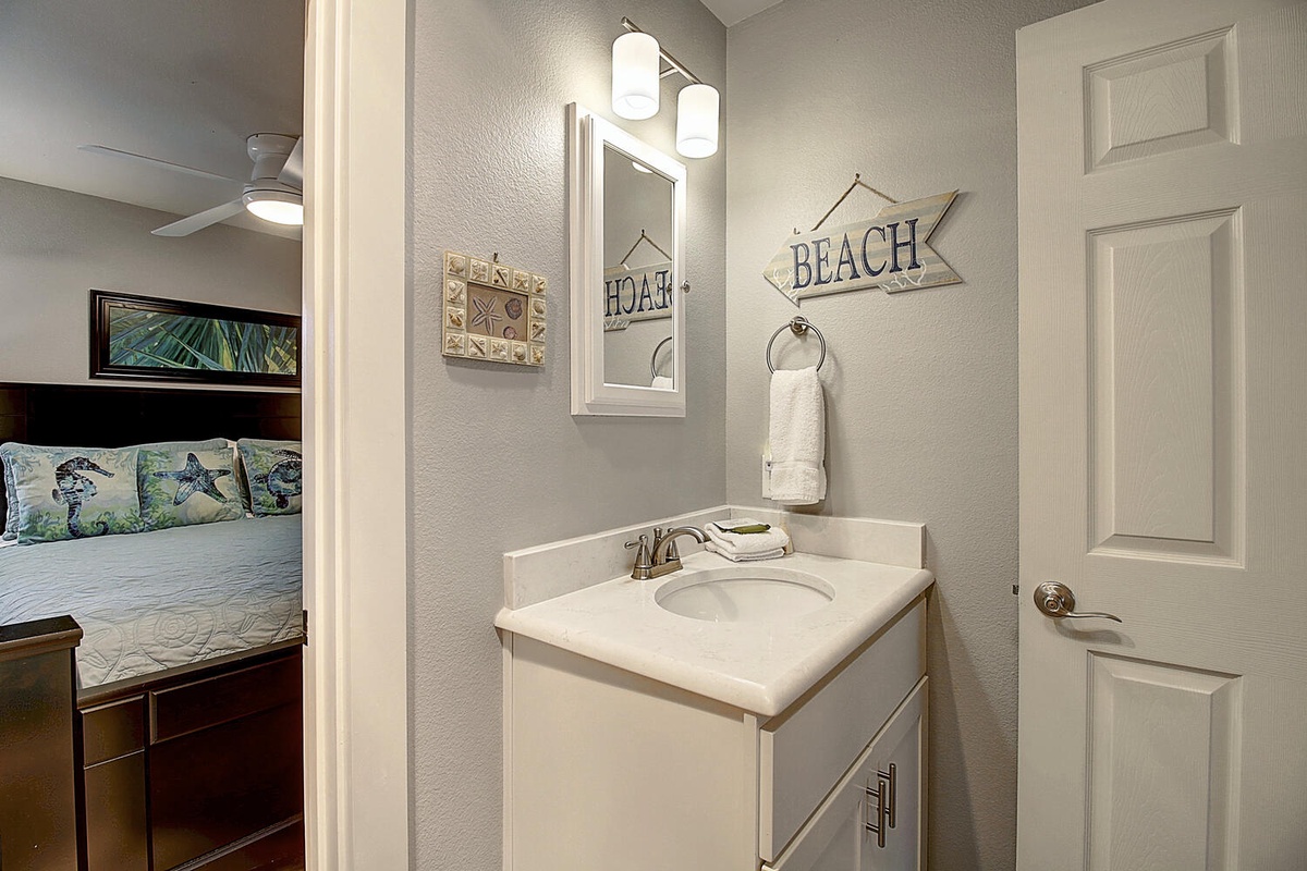 Your private ensuite vanity area features coastal charm with beach-themed decor and convenient amenities for your morning routine.