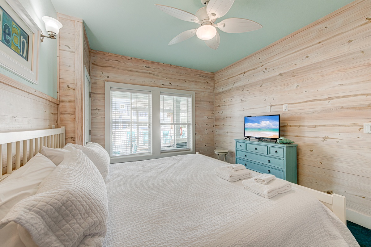 Wake up refreshed in this coastal bedroom with warm wood walls, ceiling fan, and your own TV for relaxing evenings.