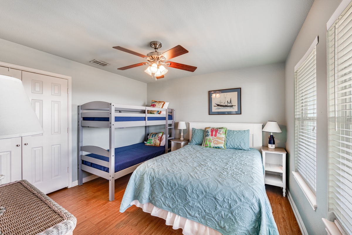 Your coastal-themed bedroom offers a queen bed plus bunk beds, perfect for families. Warm hardwood floors and ceiling fan ensure comfort.