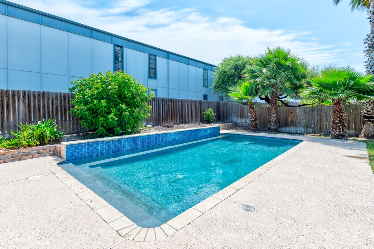 Dive into your private paradise—sparkling blue waters surrounded by tropical palms and lush landscaping create the perfect backyard oasis for relaxation.