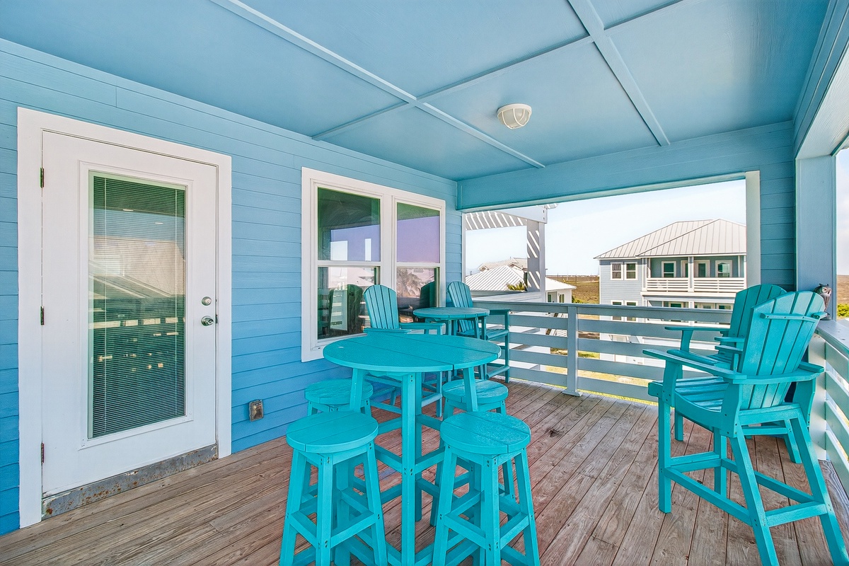 Your private covered deck awaits with cheerful turquoise furniture, perfect for morning coffee or sunset cocktails overlooking the neighborhood.