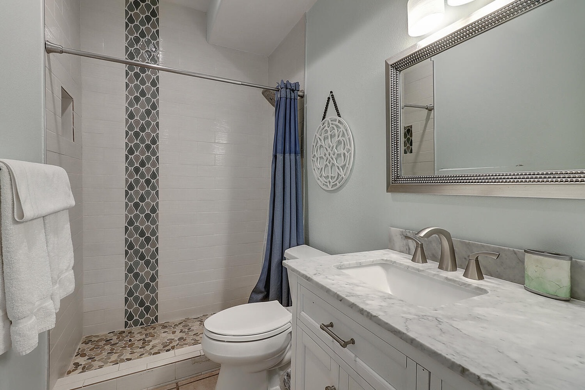 Refresh in your stylish bathroom featuring a marble vanity, mosaic tiles, and spa-like finishes for your comfort.