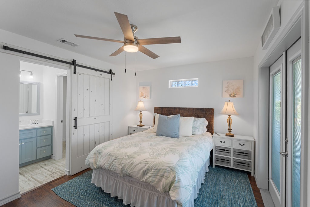 Drift off in your serene coastal bedroom with soft linens, gentle ceiling fan, and charming barn door leading to your private ensuite.