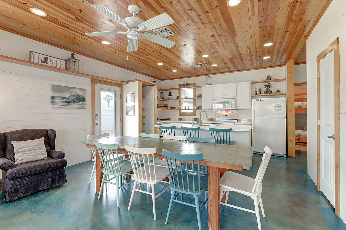 Gather around the handcrafted dining table beneath soaring wood ceilings, where coastal charm meets modern comfort in your open-concept retreat.