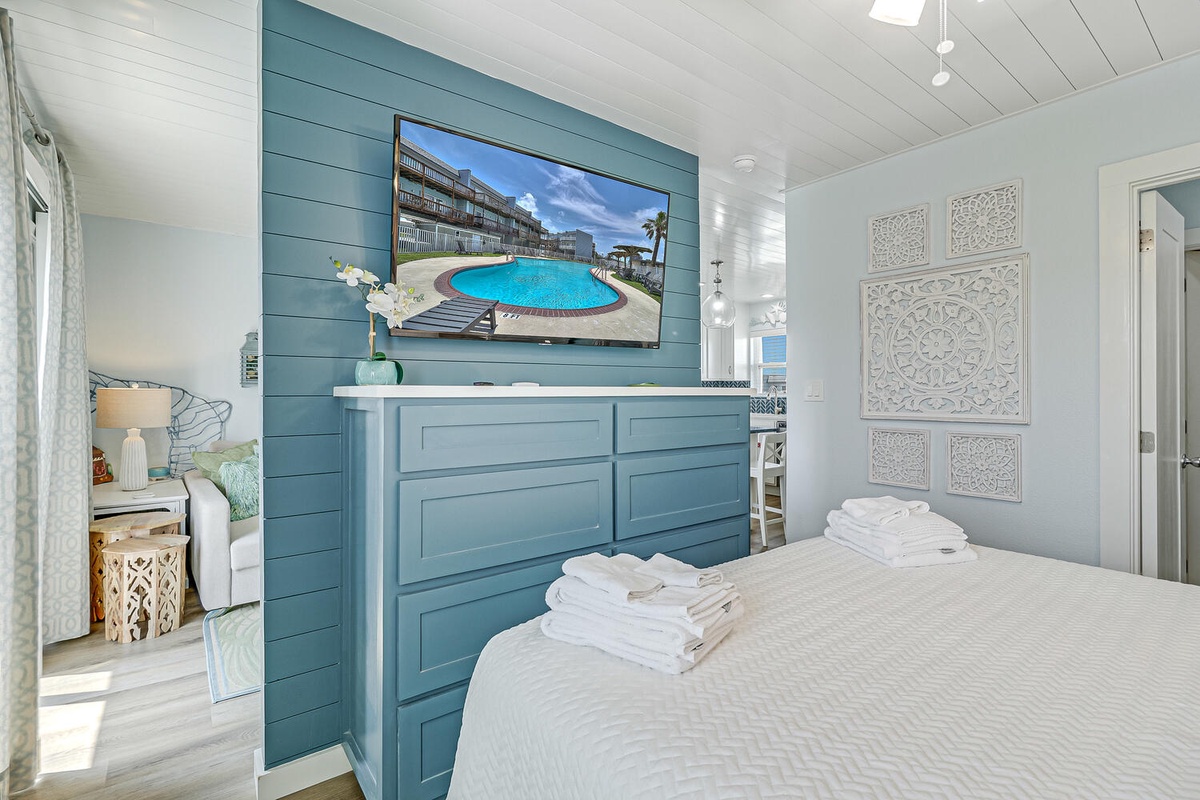 Unwind in your coastal bedroom featuring fresh linens, calming blue tones, and a large TV for your evening entertainment.