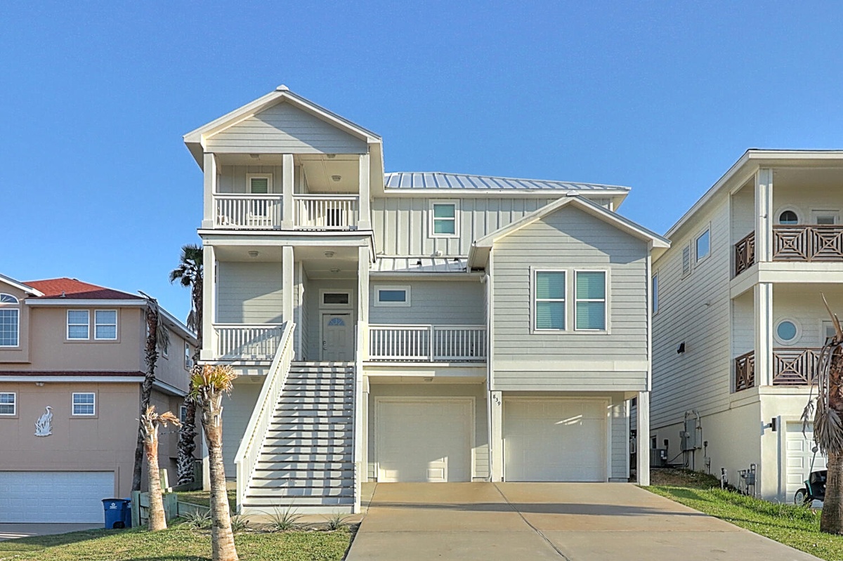 A beautiful coastal vacation home featuring multiple balconies and charming beach architecture in a quiet residential neighborhood.