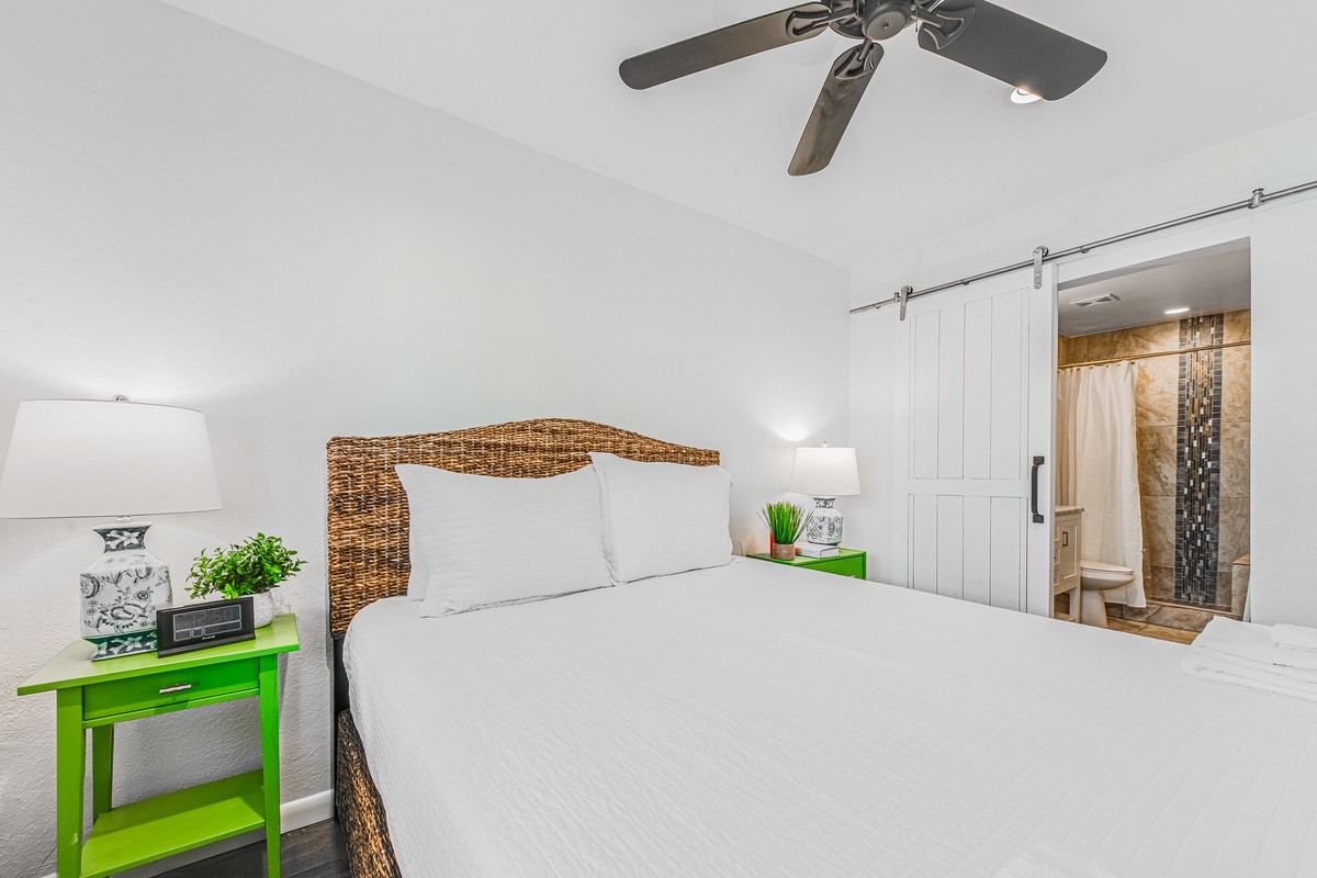 Sink into crisp white linens on your wicker headboard bed, with vibrant green nightstands adding charm to your peaceful retreat.