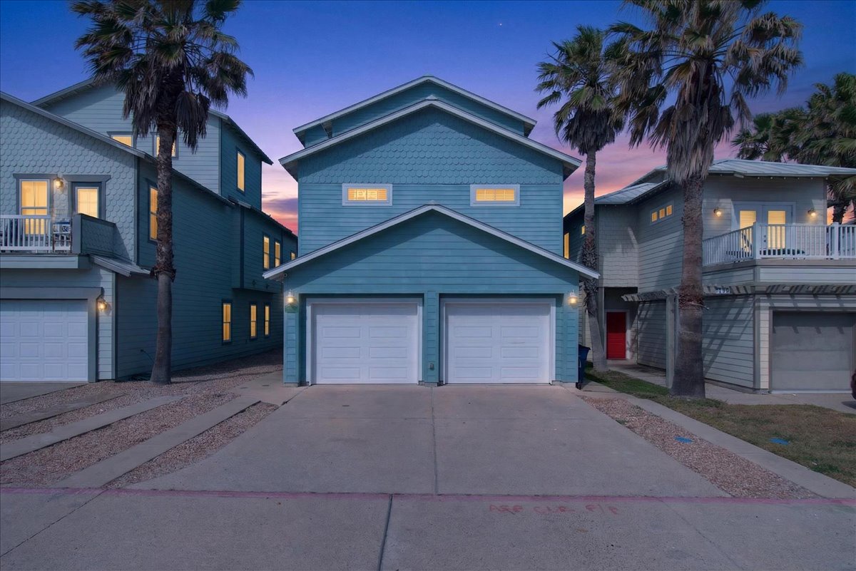 Coastal-style vacation home with tropical palm trees and sunset skies creating the perfect beachside retreat atmosphere.