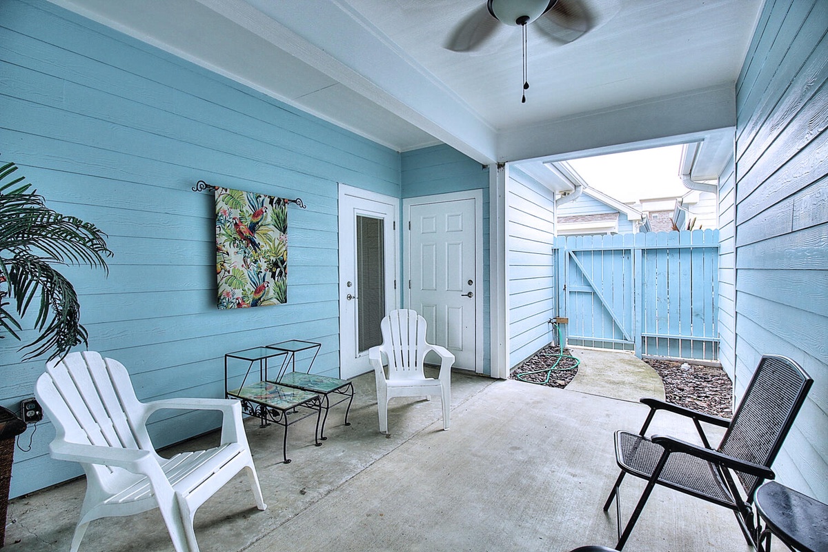 Relax on your private covered patio with coastal blue walls, comfortable seating, and tropical touches for peaceful outdoor moments.