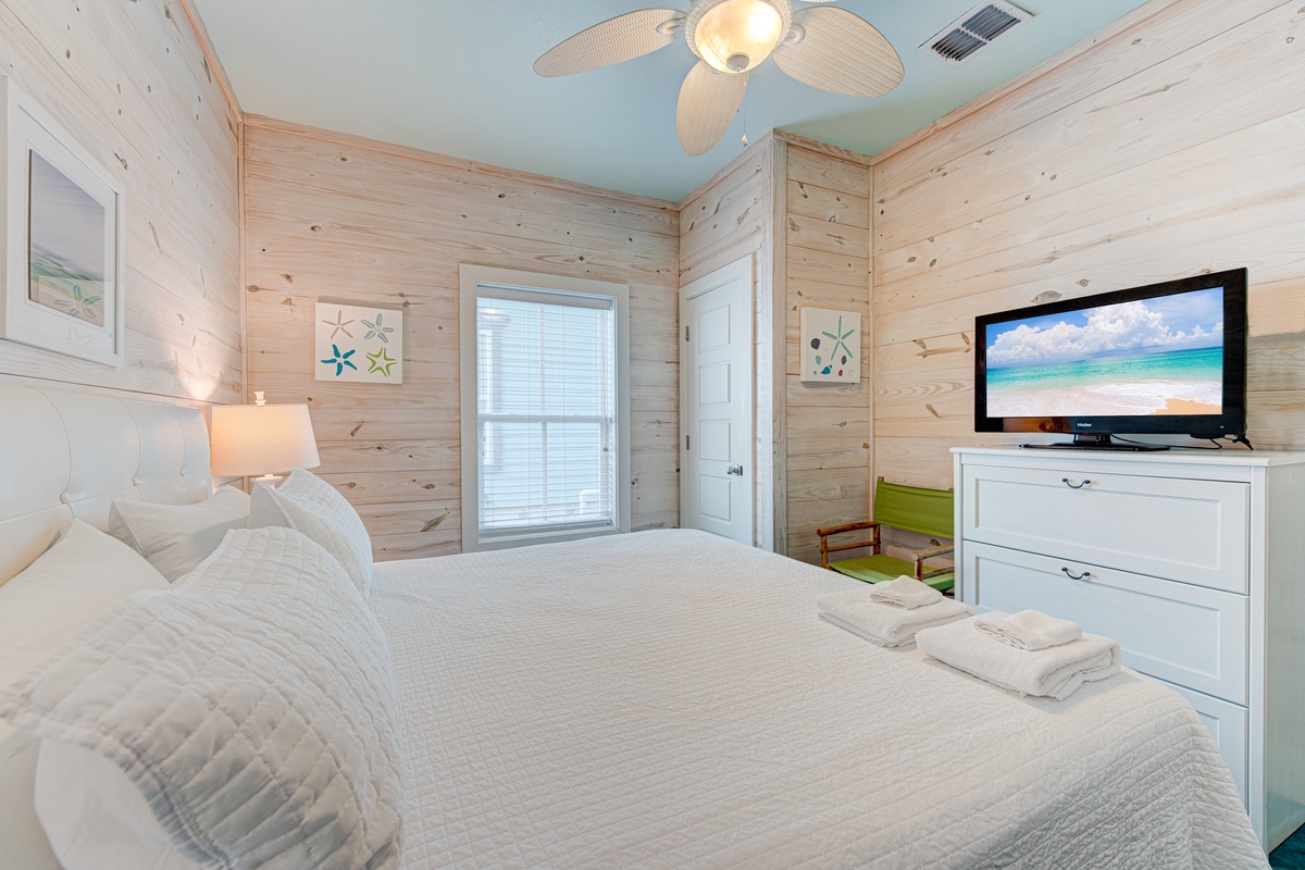 Your coastal bedroom sanctuary features crisp white linens, warm wood walls, and beachy décor that instantly relaxes you.