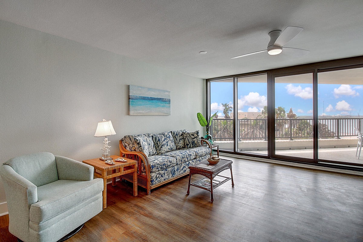 Unwind in your spacious living room where tropical breezes flow through floor-to-ceiling windows, revealing stunning views of swaying palms and endless skies.