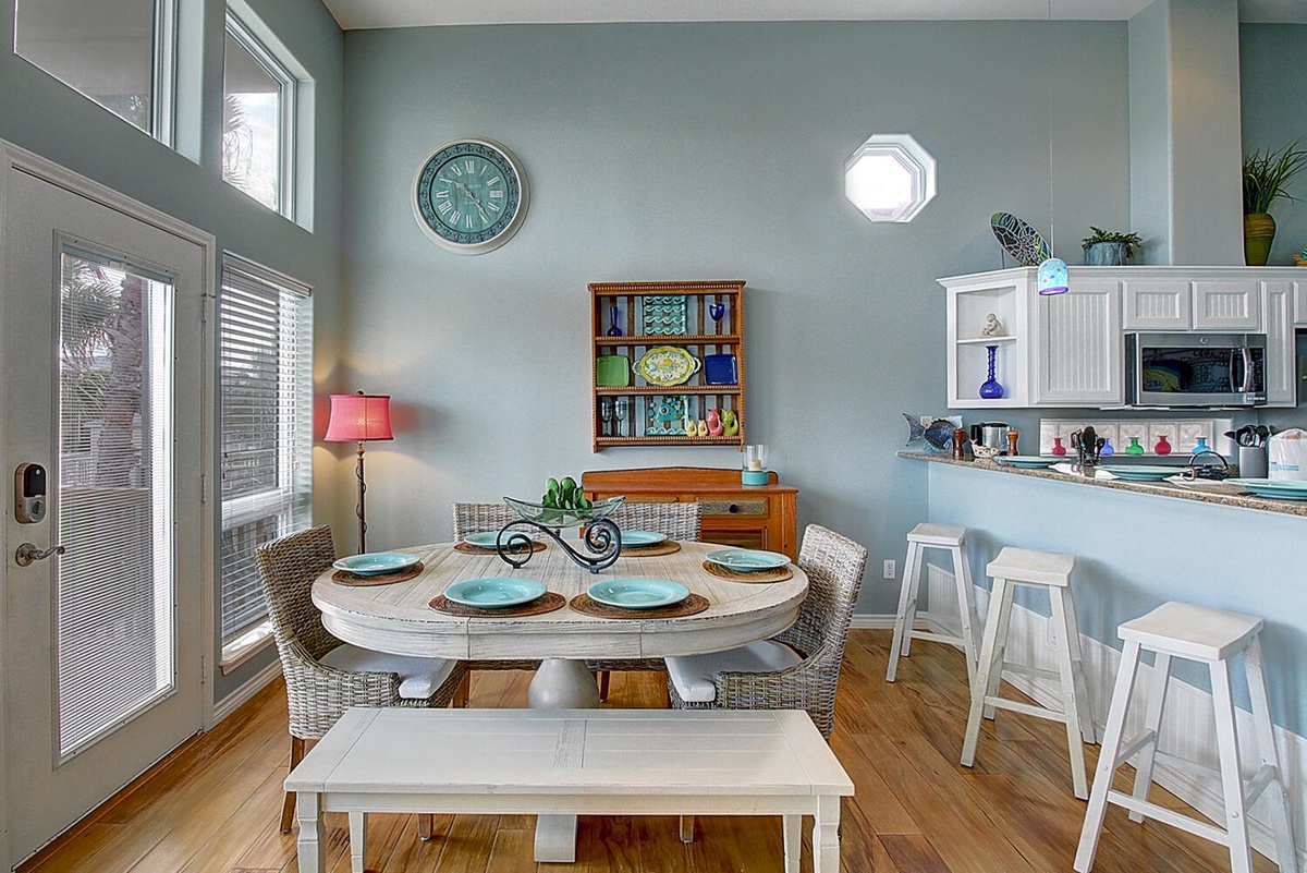 Savor meals in your bright dining space featuring coastal blues, wicker chairs, and an open kitchen perfect for vacation cooking.
