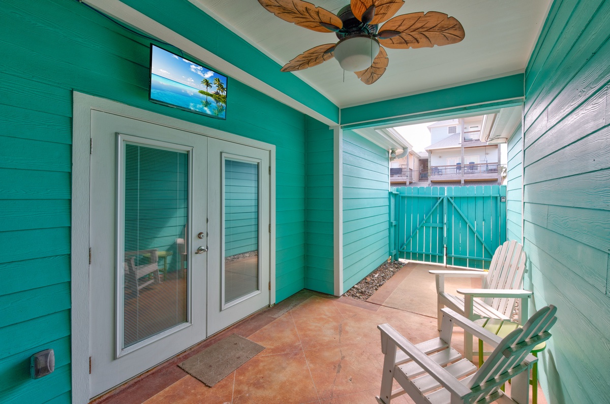 Your private covered patio offers tropical charm with cheerful turquoise walls, ceiling fan, and comfortable seating for morning coffee or evening relaxation.