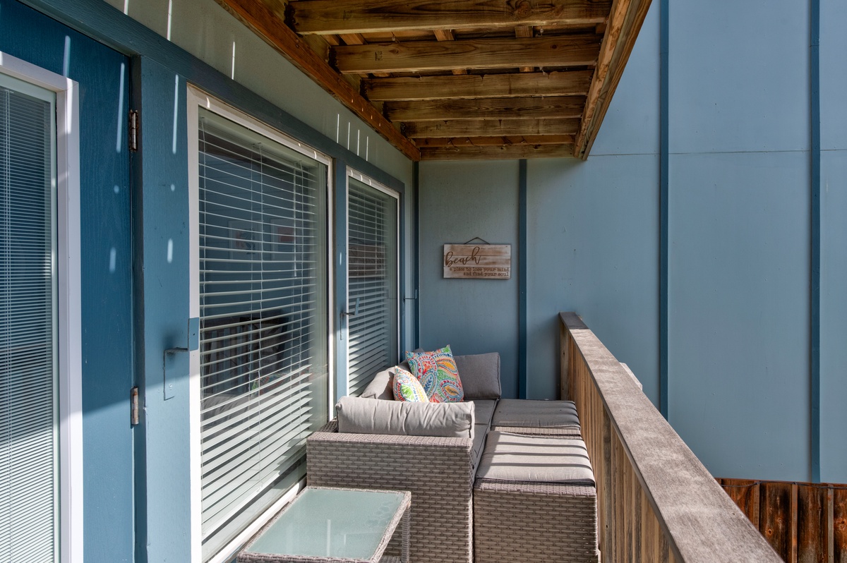 Relax on your private covered balcony with comfy seating and peaceful views through shuttered windows.