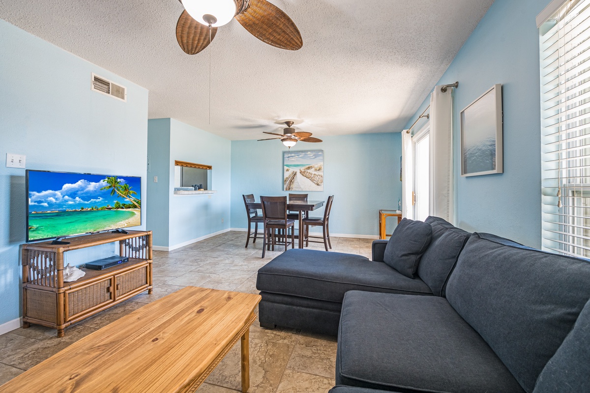Relax in your coastal-inspired living space with calming blue walls, comfortable seating, and tropical ceiling fans creating the perfect beach getaway atmosphere.