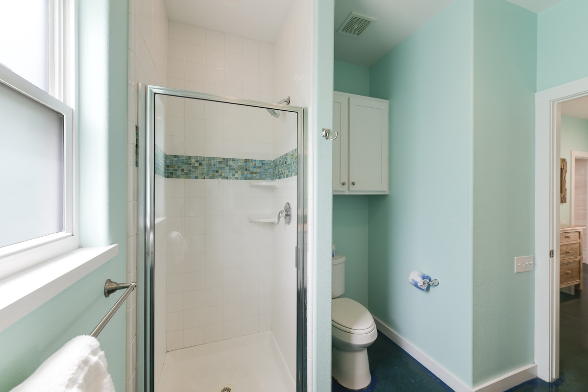 Step into your serene bathroom with soothing mint walls, sparkling tile shower, and fresh towels waiting for your relaxing retreat.