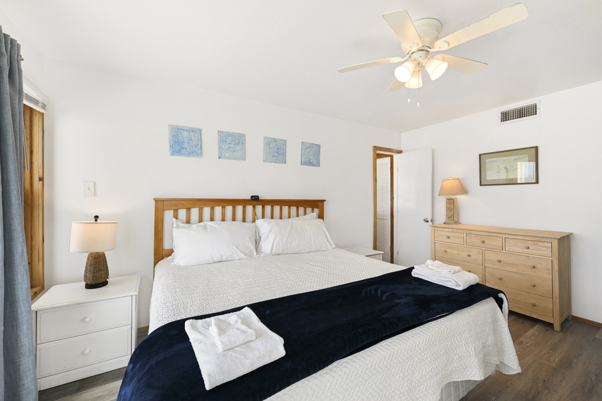 Your serene bedroom features a comfy bed with crisp linens, coastal artwork, and a ceiling fan to keep you cool. Wake up refreshed and ready to explore.