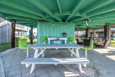 Gather around your own covered outdoor dining space, where fresh air meets comfort beneath vibrant green beams.