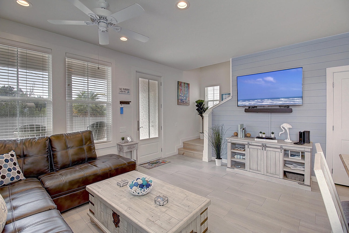 Relax in your stylish living room with leather seating, coastal decor, and a large TV for movie nights after beach days.