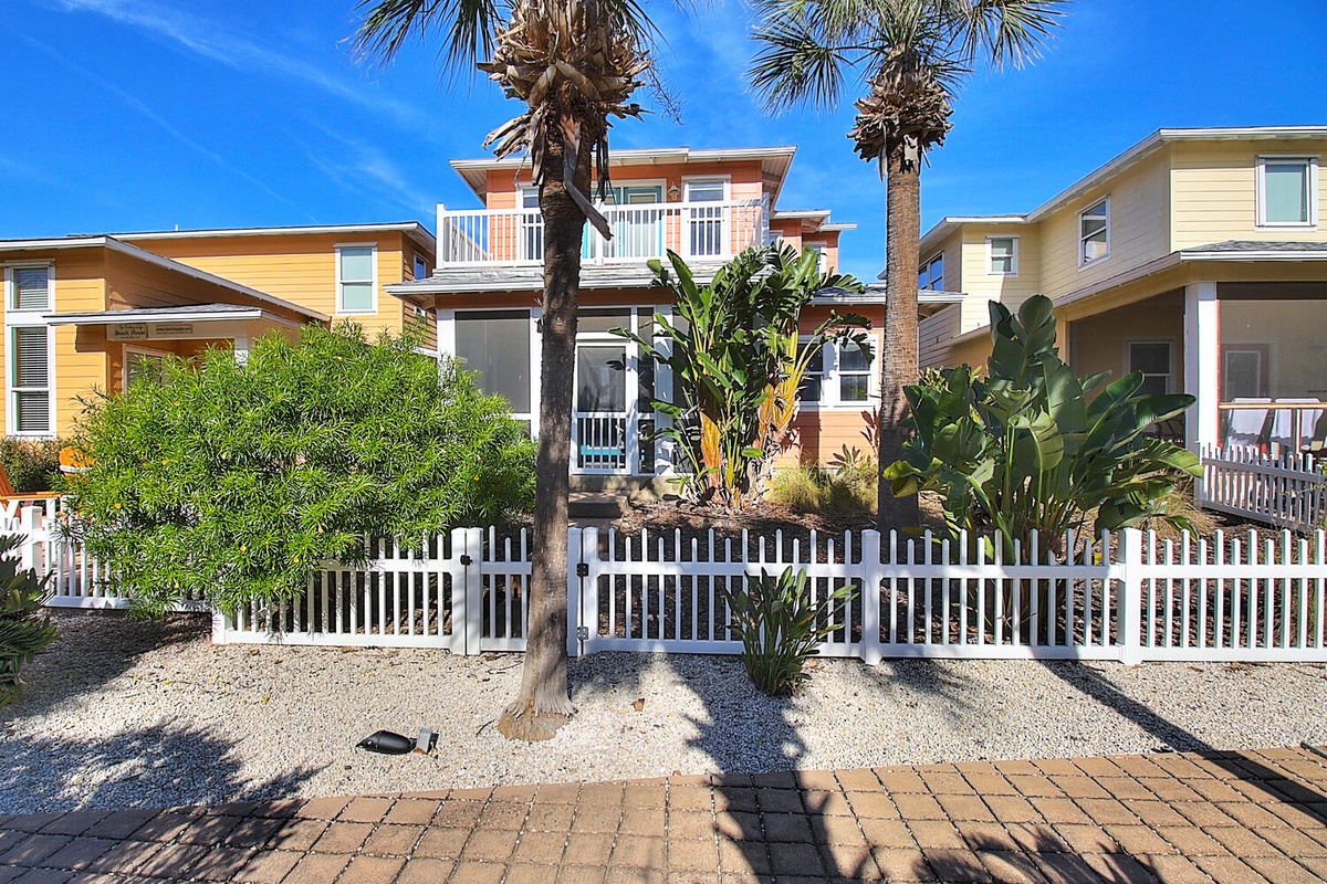 Tropical beach houses with palm trees and lush landscaping create a vibrant coastal neighborhood setting.