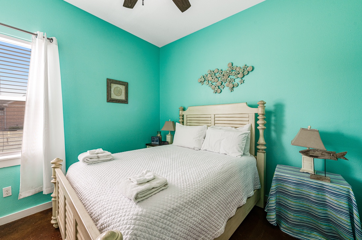 Your serene coastal bedroom awaits with soothing turquoise walls, crisp linens, and beachy décor that instantly melts away stress.