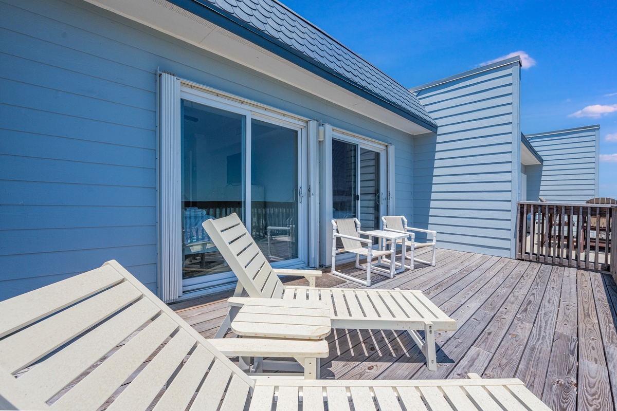 Spacious wooden deck with comfortable lounge chairs and dining set, perfect for morning coffee or evening relaxation under the open sky.