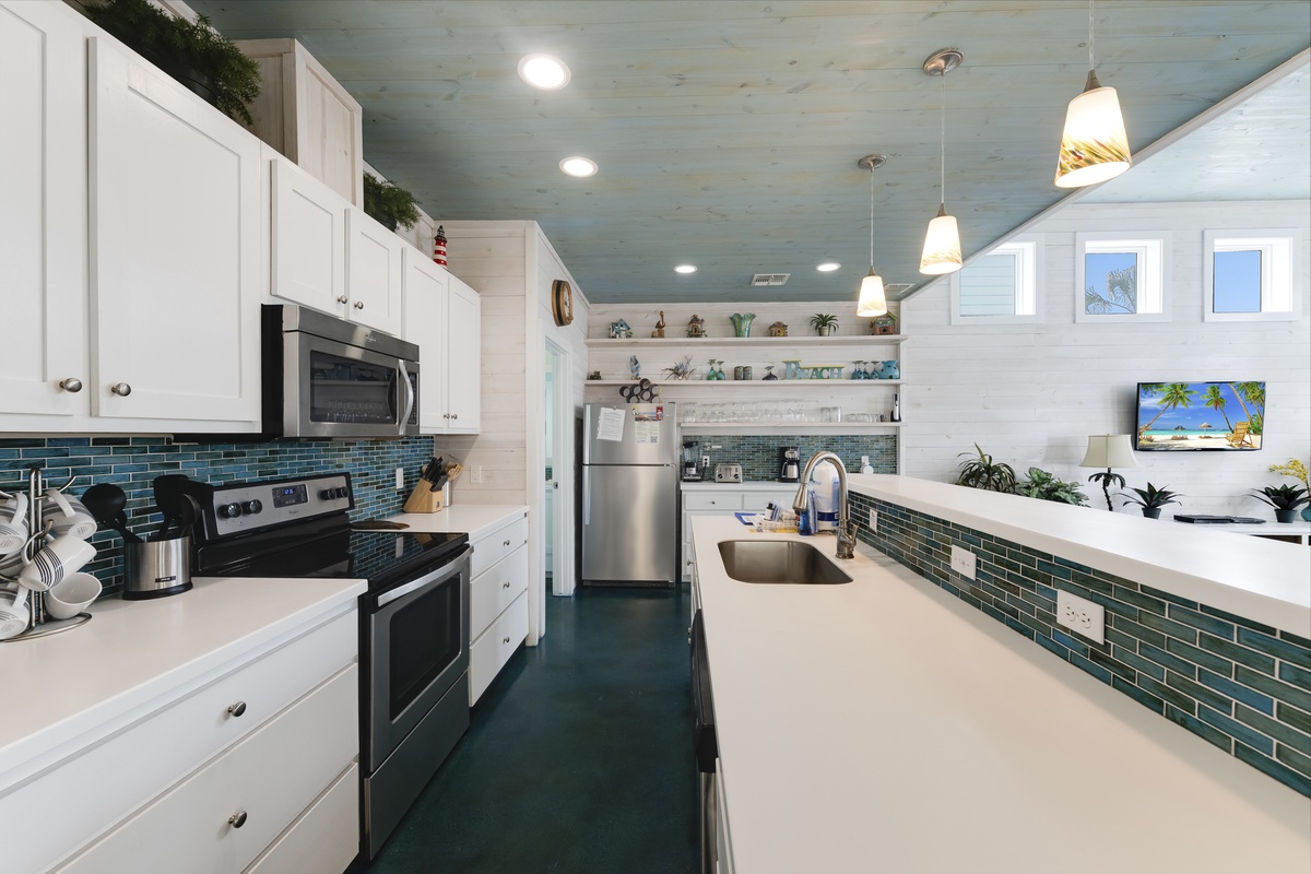Your gourmet kitchen features crisp white cabinets, stunning teal tile backsplash, and stainless appliances—perfect for preparing memorable meals together.