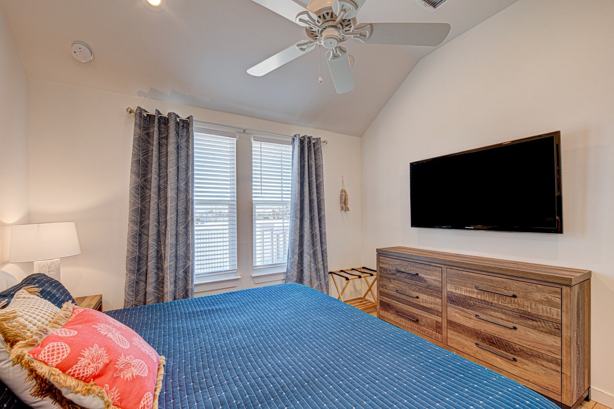 Unwind in your peaceful bedroom featuring a plush bed, ceiling fan for comfort, and entertainment center for relaxing evenings.