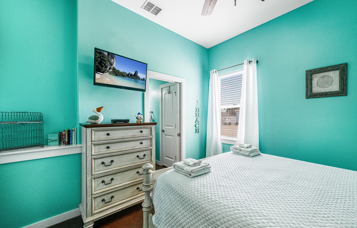 Drift into peaceful dreams in this vibrant turquoise bedroom, complete with comfortable furnishings and coastal charm.