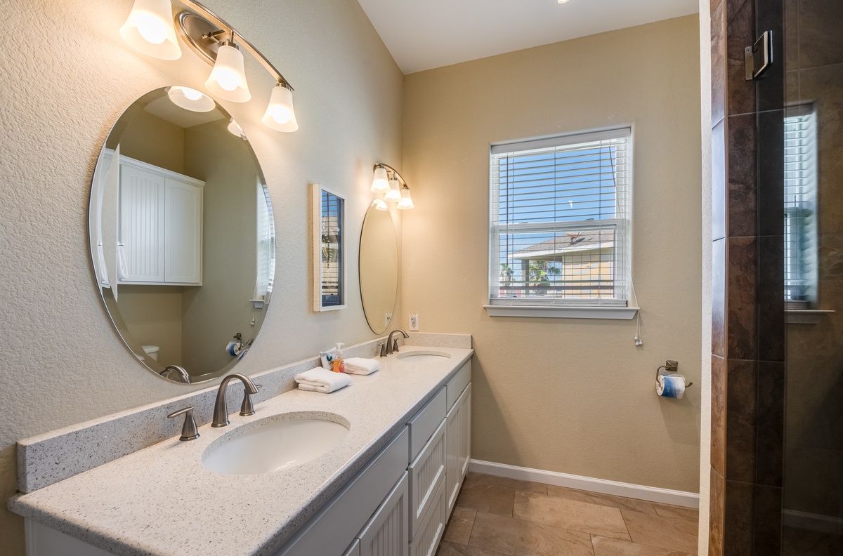 Step into your elegant en-suite bathroom featuring dual vanities, premium finishes, and a luxurious glass-enclosed shower for your comfort.
