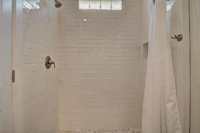 Step into your bright, clean shower with crisp white tiles and a rainfall showerhead for a refreshing start to your day.