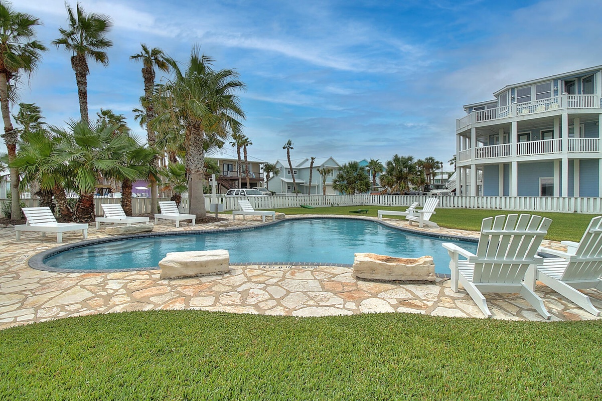 Dive into your private oasis with this sparkling pool surrounded by tropical palms and comfortable loungers for ultimate relaxation.