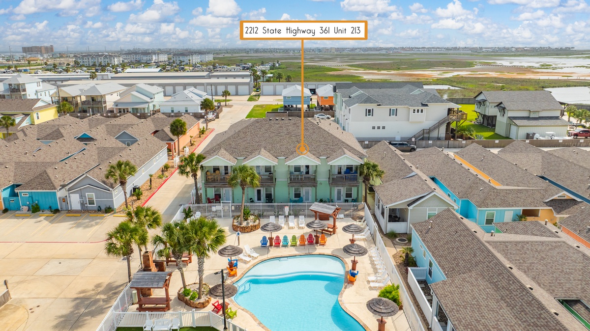 Aerial view of beachside resort with swimming pool and colorful vacation rental units near State Highway 361.