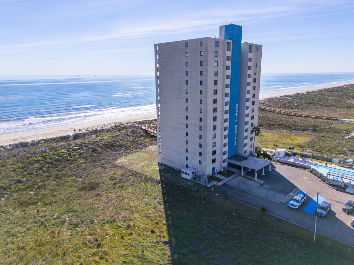 Oceanfront high-rise property situated directly on pristine beachfront with natural coastal vegetation and convenient parking facilities.